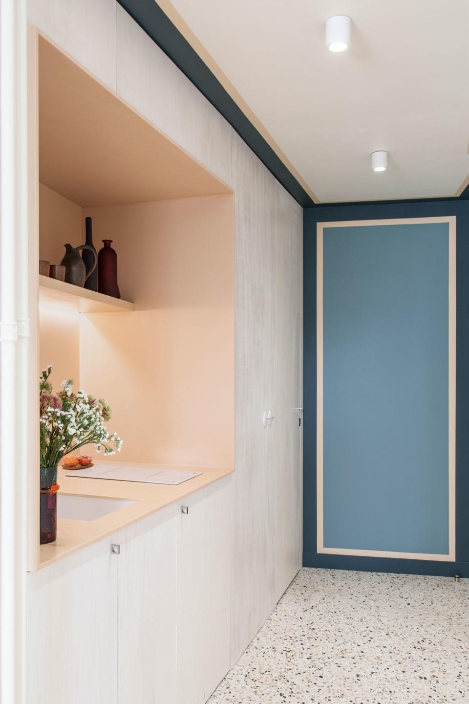 The kitchen, carved out of one of the walls of built-ins, is peachy Corian, a material Batiik has returned to time and again for its durability (this is a vacation rental apartment, after all).