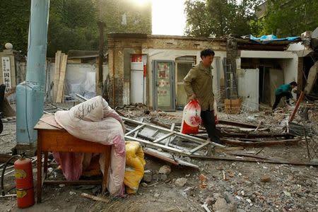 FILE PHOTO: A man carries sacks from a recently demolished house in a hutong neighborhood near the Forbidden City in Beijing, China April 20, 2017. REUTERS/Thomas Peter/File Photo