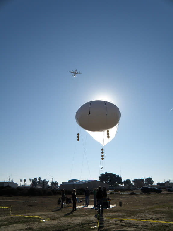 A NASA research plane flies over a tethered rheostat balloon in Huron, Calif., during a mission to improve air quality monitoring.