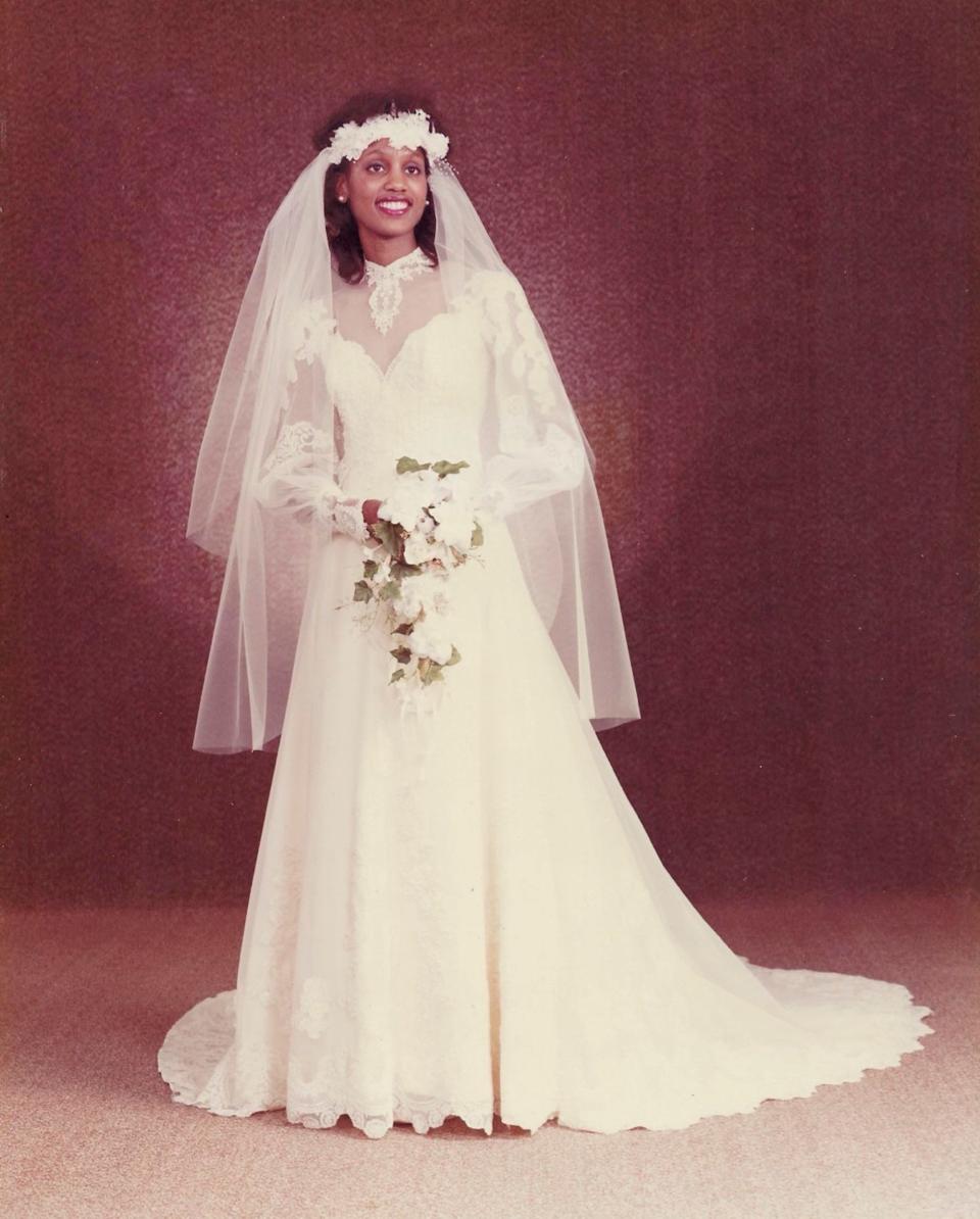 A bride in a long sleeve dress and veil poses for a photo.