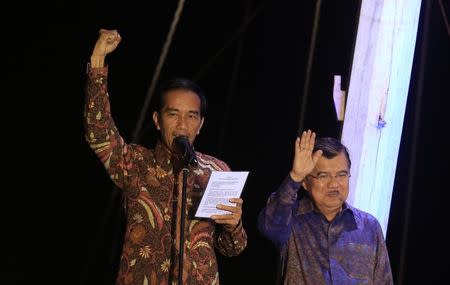 Indonesian presidential candidate Joko "Jokowi" Widodo (L) gestures as delivers a speech, beside his running mate Jusuf Kalla, on a phinisi boat, a traditional Indonesian ship, at Sunda Kelapa port after he was declared the winner of the presidential election in Jakarta July 22, 2014. REUTERS/Beawiharta