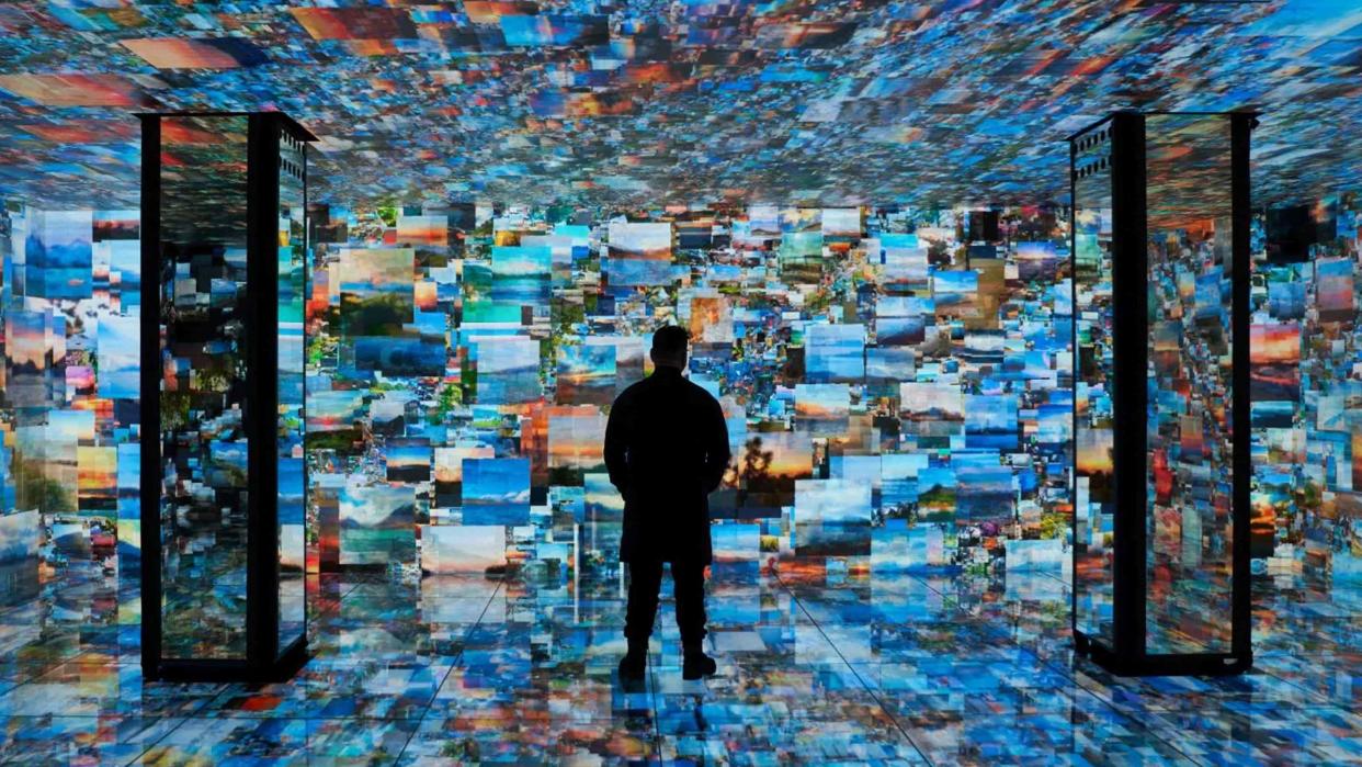  A man stands in front of many high-tech images in a technology zone at ISE. 