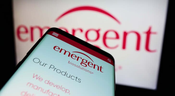 A mobile phone displays the website for Emergent Biosolutions (EBS)