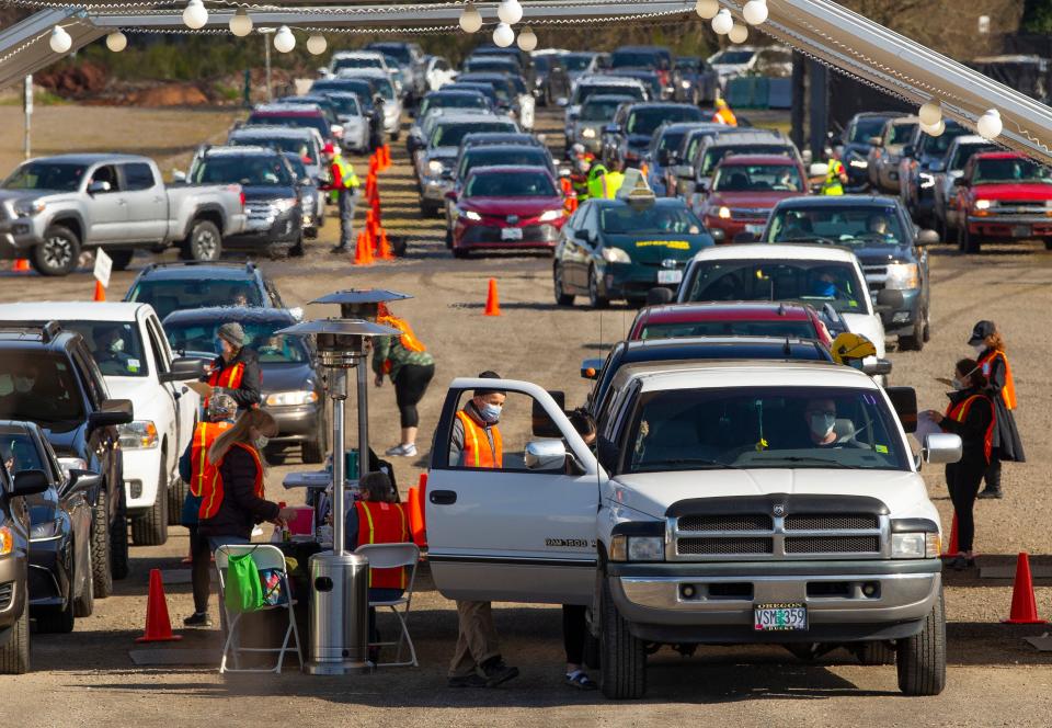 Cars full of people wanting a COVID-19 vaccine line up in the parking lot of Autzen Stadium in Eugene, Ore., on March 27.