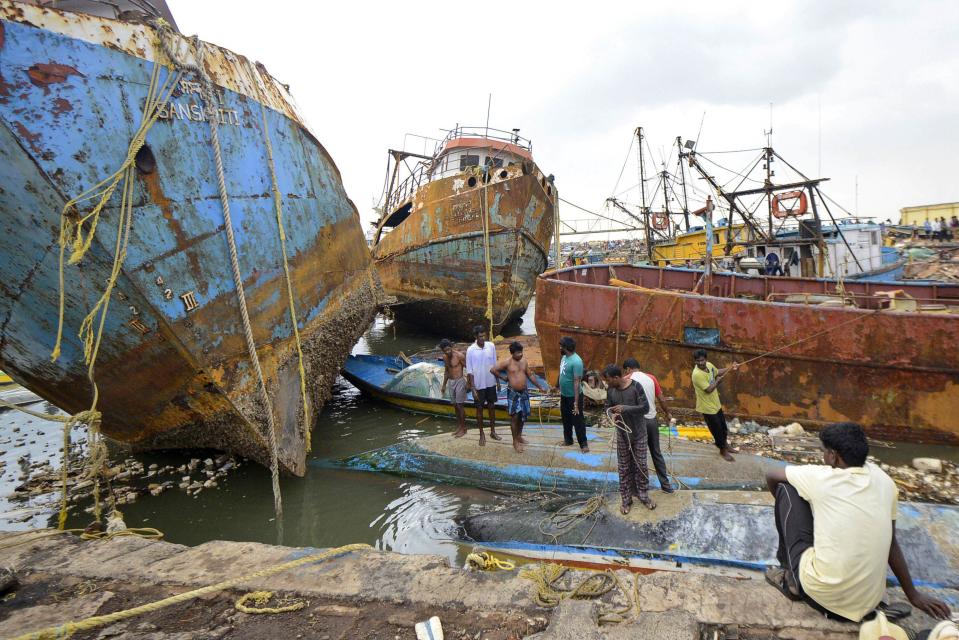 People stand on boats damaged by strong winds caused by Cyclone Hudhud in the southern Indian city of Visakhapatnam October 13, 2014. Cyclone Hudhud powered its way inland over eastern India on Monday, leaving a swathe of destruction but the loss of life appeared limited after tens of thousands of people sought safety in storm shelters, aid workers and officials said. REUTERS/R Narendra (INDIA - Tags: DISASTER ENVIRONMENT TPX IMAGES OF THE DAY)