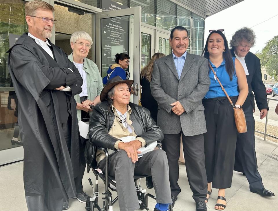 Allan Woodhouse, seated, and Brian Anderson, hands clasped in front of him, stand outside the Winnipeg Law Courts Building after a judge tossed out their murder convictions from 1974. 