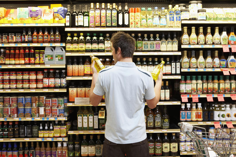 Person comparing two bottles in a grocery store aisle