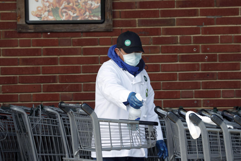 A Whole Foods Market worker cleans grocery carts in Durham, N.C., Wednesday, April 15, 2020. This week, Gov. Roy Cooper set new social-distancing and cleaning mandates that essential retailers must follow in order to stay open. Stay at home orders remain in effect throughout the state due to the coronavirus. (AP Photo/Gerry Broome)