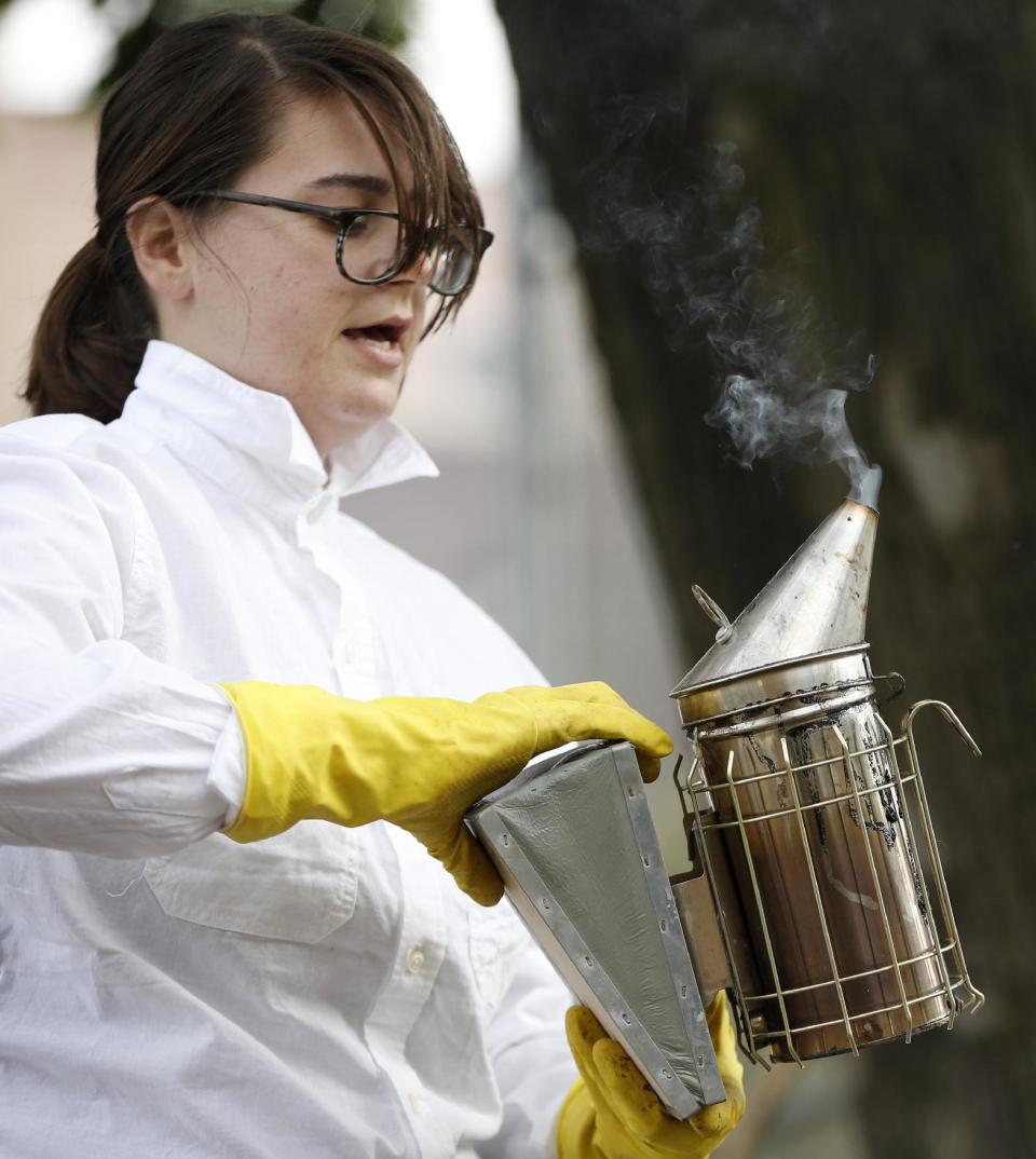 In this Wednesday, Oct. 16, 2013 photo, Beekeeper Kellen Henry checks her smoker before conducting a hive inspection at a Feedback Farms hive in Myrtle Village Green community garden in the Bedford-Stuyvesant section of Brooklyn, in New York. The smoke calms the bees during the inspection. Though New York reversed a long-standing ban on tending to honeybees in 2010, there are issues beyond legality that potential beekeepers should consider. Beekeeping, especially in an urban area, requires space, time and cooperation with the surrounding community. (AP Photo/Kathy Willens)