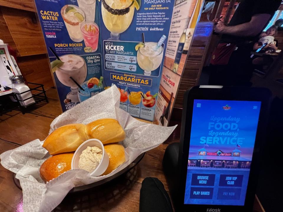 Warm rolls and butter, a menu, and a mini kiosk at a Texas Roadhouse