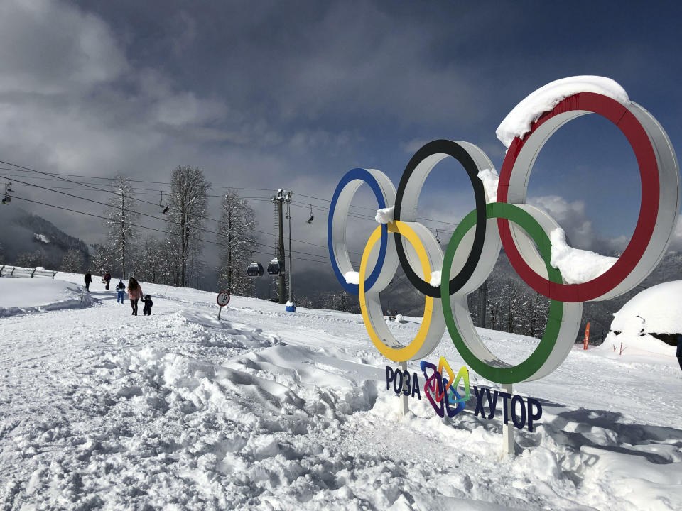 In this photo taken on Sunday, March 3, 2019, tourists walk next to the Olympic rings on the mountain resort of Krasnaya Polyana near the Black Sea resort of Sochi, southern Russia. In the five years since the Sochi Olympics, Russians have been flocking south to enjoy their subtropical ski slopes. (AP Photo/James Ellingworth)