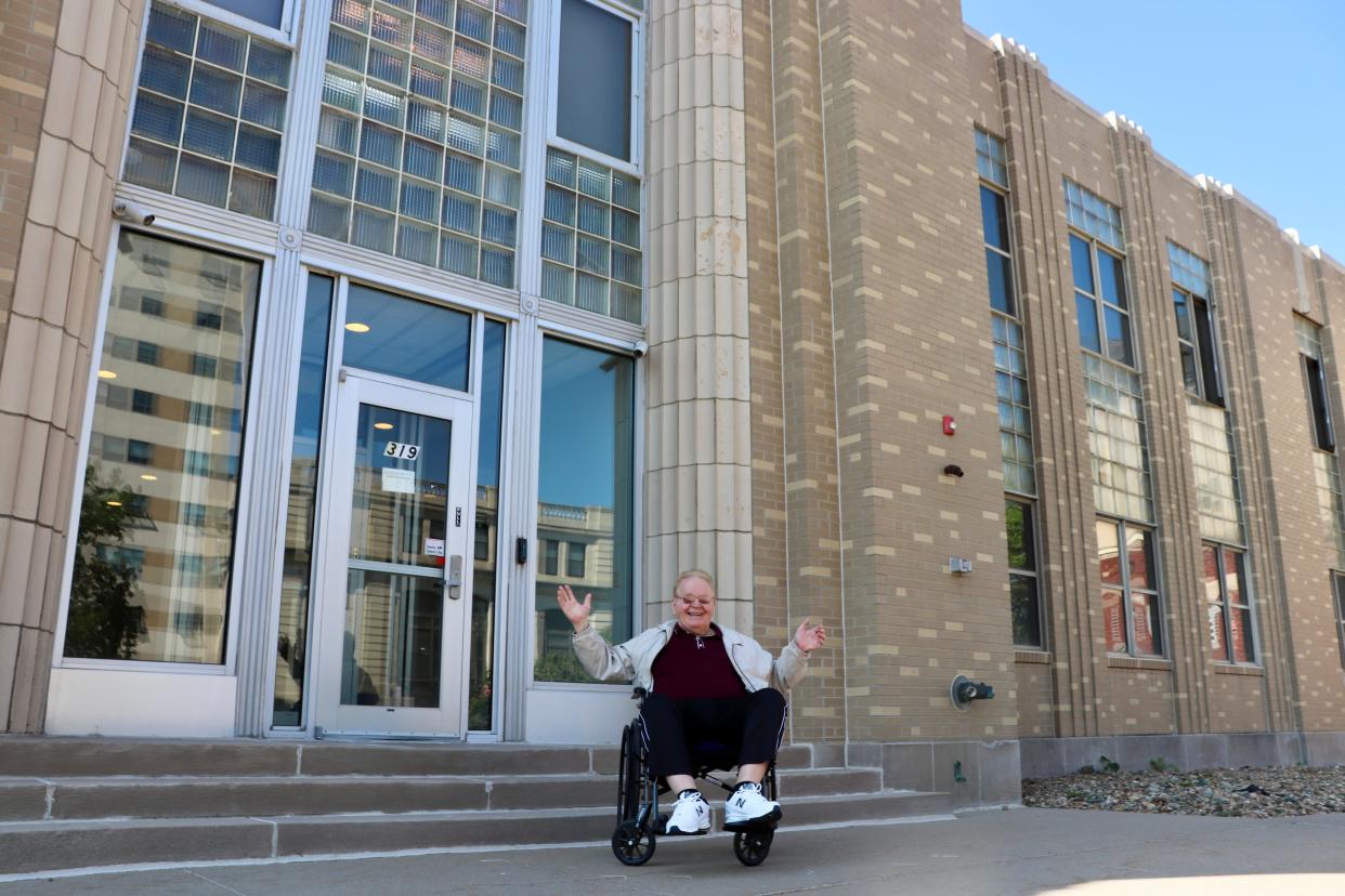 David Wood throws his hands up in celebration and poses for a photo in front of the old Iowa City Press-Citizen building at 319 E. Washington St. on Friday, Aug. 18, 2023. Wood first started delivering papers as a six-year-old in 1949.