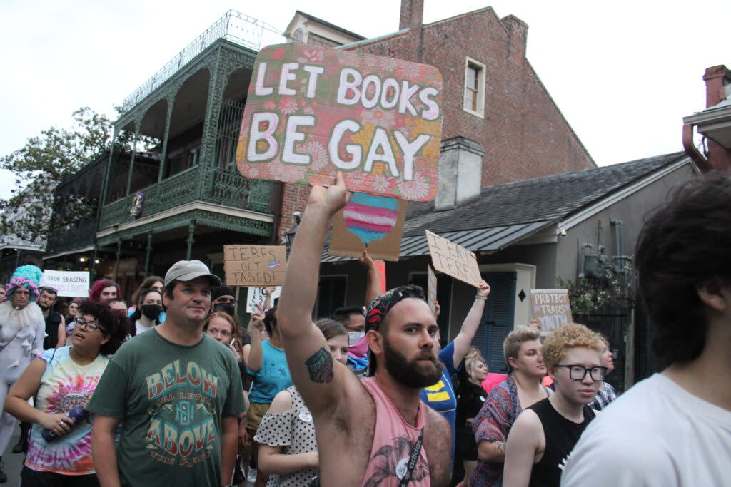 A marchers carries a sign that says "Let Books Be Gay" as they walk through the French Quarter in New Orleans for Transgender Day of Visibility on March 31, 2023.