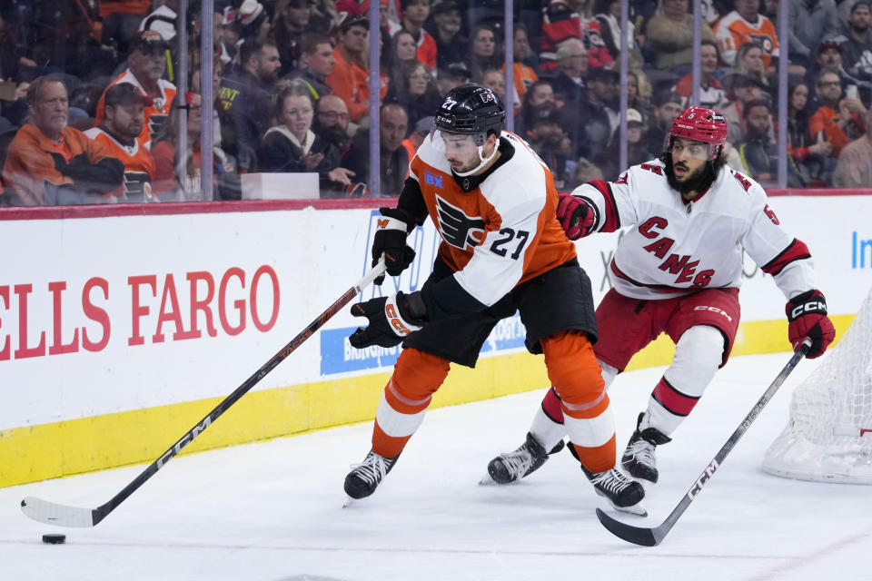 Philadelphia Flyers' Noah Cates, left, tries to keep away from Carolina Hurricanes' Jalen Chatfield during the second period of an NHL hockey game, Monday, Oct. 30, 2023, in Philadelphia. (AP Photo/Matt Slocum)