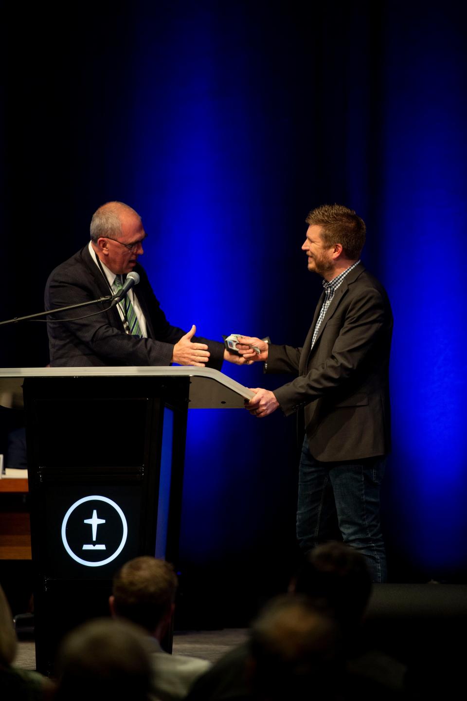 Bart Barber, Southern Baptist Convention president, offers some money to Josh Wester, a North Carolina pastor and chairman of the SBC's Abuse Reform Implementation Task Force, during the SBC Executive Committee meeting in February in Nashville.