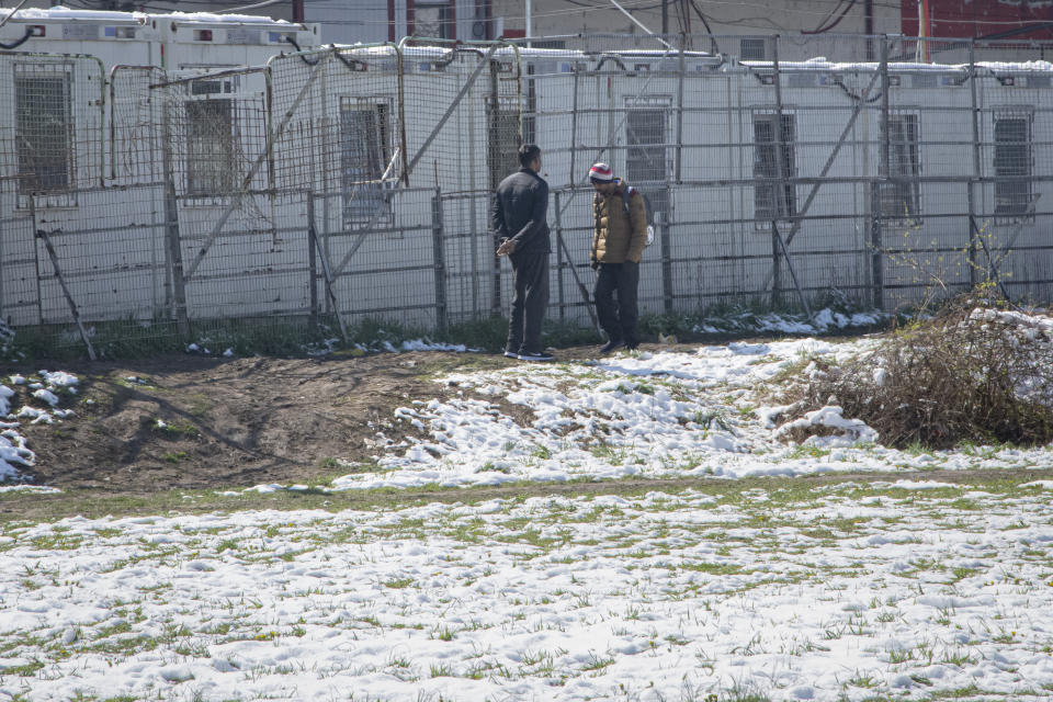 Migrants walk outside the Miral camp, in Velika Kladusa, Bosnia, Wednesday, April 7, 2021. Bosnia is seeing a rise in coronavirus infections among migrants and refugees living in its camps, as it struggles to cope with one of the Balkans' highest COVID-19 death and infection rates among the general population.(AP Photo/Davor Midzic)