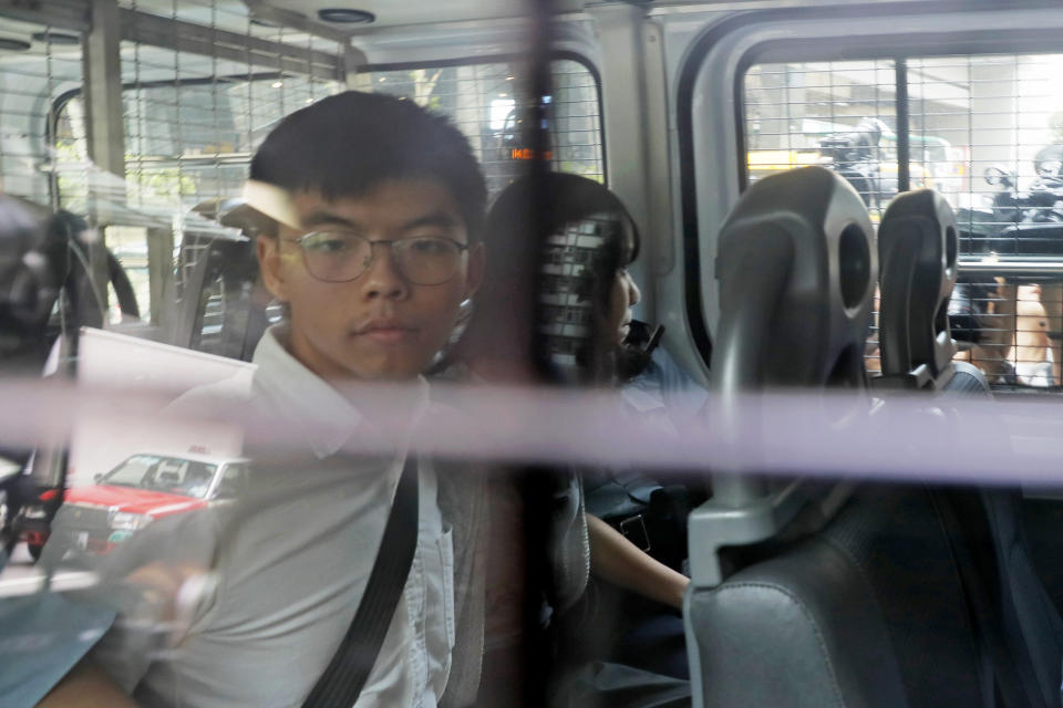 Pro-democracy activists Joshua Wong, left, and Agnes Chow, are escorted in a police van at a district court in Hong Kong, Friday, Aug. 30, 2019. Hong Kong police arrested well-known activist Wong and Chow, another core member of a pro-democracy group, Friday, and authorities denied permission for a major march in what appears to a harder line on this summer's protests. (AP Photo/Kin Cheung)