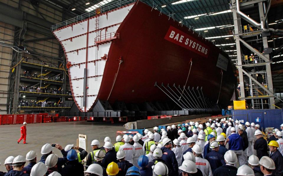 Workers watch as the forward section of the aircraft carrier HMS Queen Elizabeth is moved onto a barge at HM Naval Base in Portsmouth -  Reuters