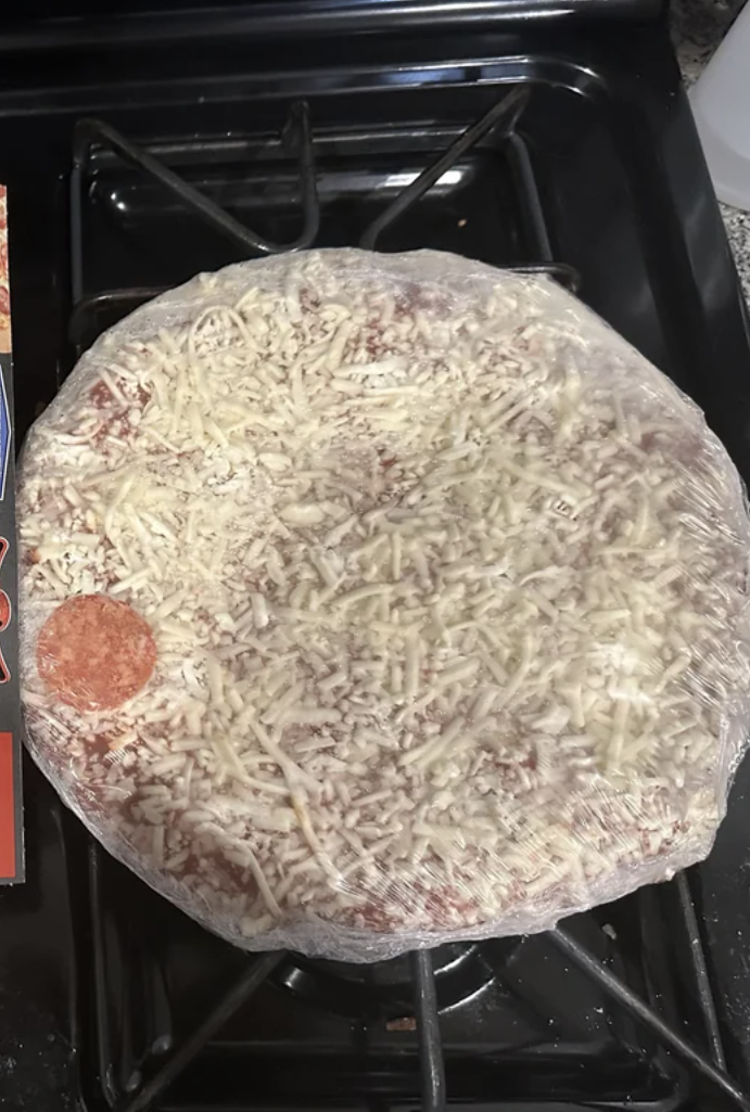 Box of Red Baron classic crust pepperoni pizza next to the actual pizza on a baking tray