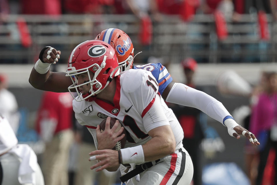 Georgia quarterback Jake Fromm, left, scrambles for yardage before he is brought down by Florida linebacker Jonathan Greenard during the first half of an NCAA college football game, Saturday, Nov. 2, 2019, in Jacksonville, Fla. (AP Photo/John Raoux)