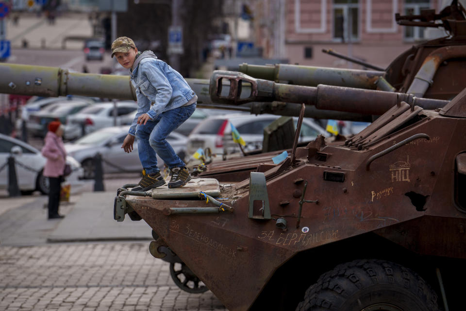 A child climbs on a rusty armored personnel carrier, part of a display of destroyed Russian military equipment in Kyiv, Ukraine, Thursday, March 28, 2024. (AP Photo/Vadim Ghirda)