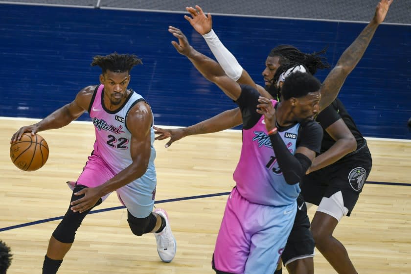Miami Heat forward Jimmy Butler (22) drives past a crowd of Minnesota Timberwolves defenders.