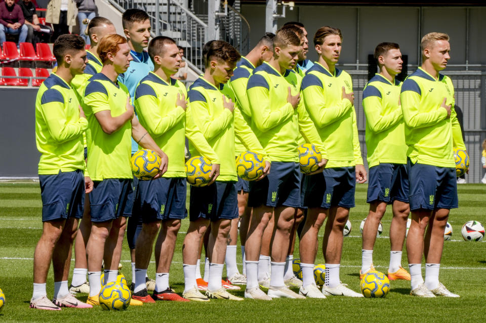 Players of Ukraine's national soccer team listen to the national anthem during a public training session in Wiesbaden, Germany, Thursday, June 13, 2024, ahead of their group E match against Romania at the Euro 2024 soccer tournament. (AP Photo/Michael Probst)