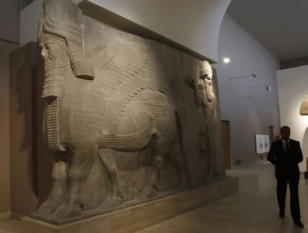A man walks past human-headed winged bull statues from Khorsabad, at the Iraqi National Museum in Baghdad March 8, 2015. REUTERS/Khalid al-Mousily