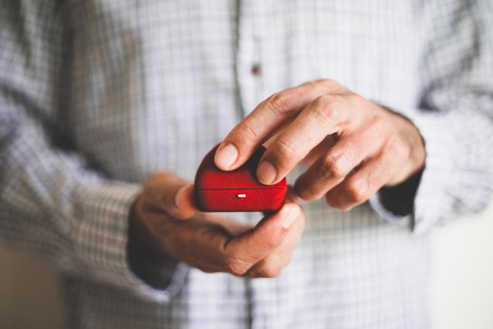 Close-up of a person holding a small red velvet ring box, suggesting a marriage proposal