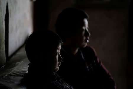 Wang Shiming (L), 11, and his brother Wang Shiqi, 13, great-grandsons of surviving villager Liu Guizhen, watch television in an old house damaged in the 2008 Sichuan earthquake, at a village on a mountain in Beichuan county, Sichuan province, China, April 6, 2018. REUTERS/Jason Lee