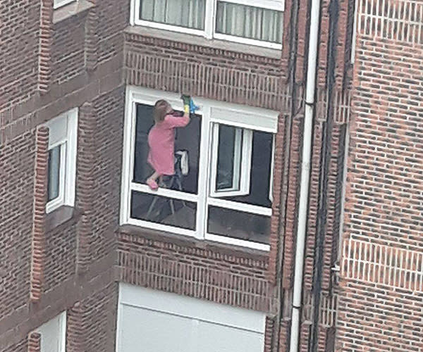 Señora lavando la cornisa de su ventana sin seguridad. Facebook.com/Cosas que pasan en Cantabria