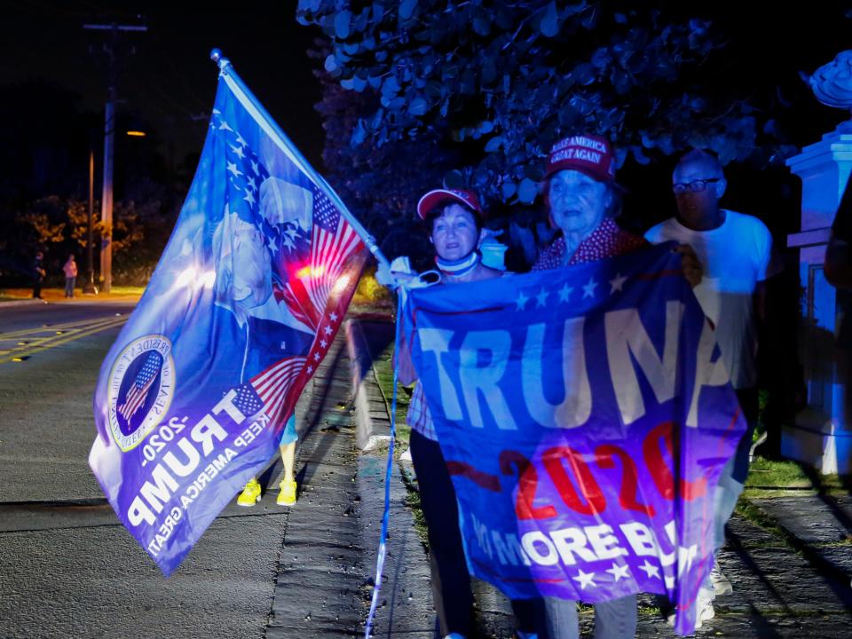 Supporters of former President Donald Trump hold flags in front of his home at Mar-A-Lago on August 8, 2022 in Palm Beach, Florida. The FBI raided the home to retrieve classified White House documents. (Photo by Eva Marie Uzcategui/Getty Images)