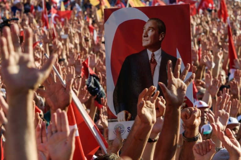 Demonstrators rise their hands and hold a potrait picture of Mustafa Kemal Ataturk, founder of modern Turkey, as they gather at Taksim Square in Istanbul on July 24, 2016