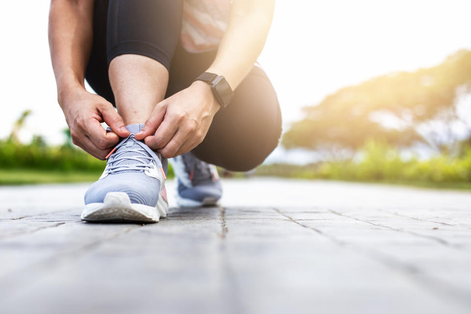 Young woman tying jogging shoes.