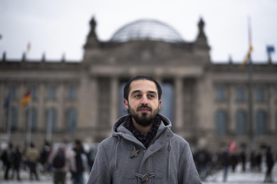 Tareq Alaows, who is running to become a lawmaker at the German parliament Bundestag poses in front of the Reichstag building in Berlin, Germany, Saturday, Feb. 6, 2021. Tareq Alaows fled the civil war in Syria in 2015, crossed the Mediterranean on a flimsy rubber boat and tracked up the Balkans, like over a million migrants looking for a save haven in Germany. Five years on, the 31-year-old Syrian has received asylum, speaks fluent German, has a job, applied for citizenship and launched his campaign to run for federal elections in Germany on Sept. 26. (AP Photo/Markus Schreiber)