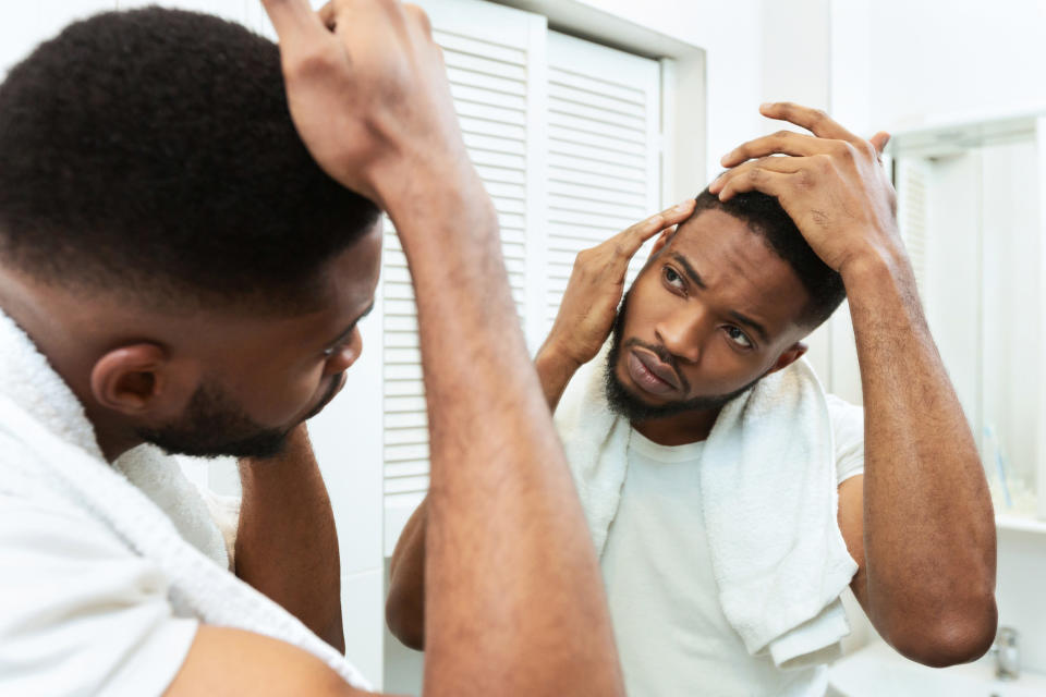 A guy critiquing his hair line in a gym