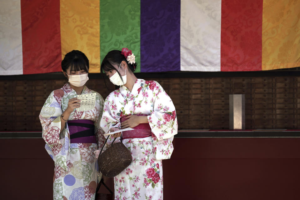 FILE - Visitors in yukatas or Japanese traditional summer kimonos wear protective masks to help curb the spread of the coronavirus as they draw a fortune-telling paper strip at the Sensoji Temple in the Asakusa district, on Sept. 20, 2021 in Tokyo. The World Health Organization said Friday May 5, 2023 that COVID-19 no longer qualifies as a global emergency, marking a symbolic end to the devastating coronavirus pandemic that triggered once-unthinkable lockdowns, upended economies and killed millions of people worldwide. (AP Photo/Eugene Hoshiko, File)