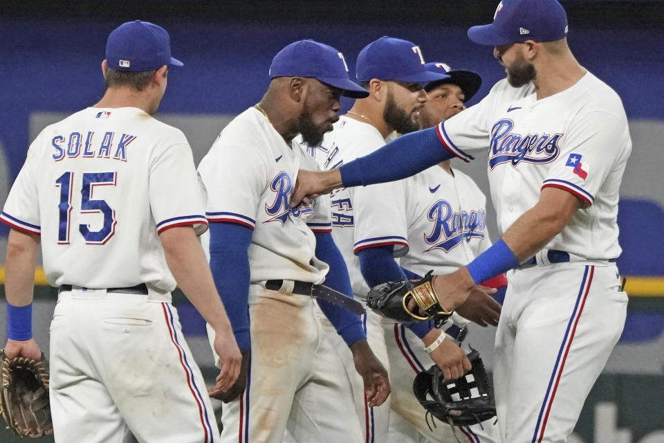 Texas Rangers center fielder Adolis Garcia, second from left, absorbs a playful punch from teammate Joey Gallo, right, as they celebrate their win over the Seattle Mariners after a baseball game Saturday, May 8, 2021, in Arlington, Texas. (AP Photo/Louis DeLuca)