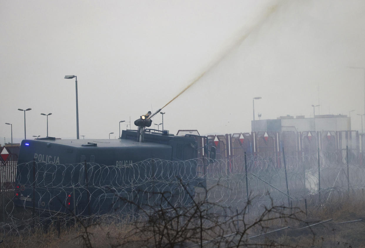 Polish servicemen use a water cannon during clashes between migrants and Polish border guards at the Belarus-Poland border near Grodno, Belarus, on Tuesday, Nov. 16, 2021. Polish border forces say they were attacked with stones by migrants at the border with Belarus and responded with a water cannon. The Border Guard agency posted video on Twitter showing the water cannon being directed across the border at a group of migrants in a makeshift camp. (Leonid Shcheglov/BelTA via AP)