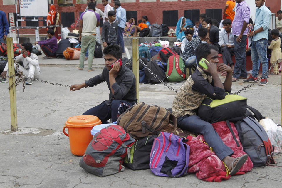 Indian migrant laborers speak on their mobile phones as they prepare to leave the region, at a railway station in Jammu, India, Wednesday, Aug. 7, 2019. Indian lawmakers passed a bill Tuesday that strips statehood from the Indian-administered portion of Muslim-majority Kashmir, which remains under an indefinite security lockdown, actions that archrival Pakistan warned could lead to war. (AP Photo/Channi Anand)