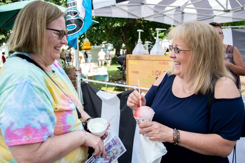 Two friends share a laugh over snowcones and homemade ice cream at the Salt Fork Arts and Crafts Festival.