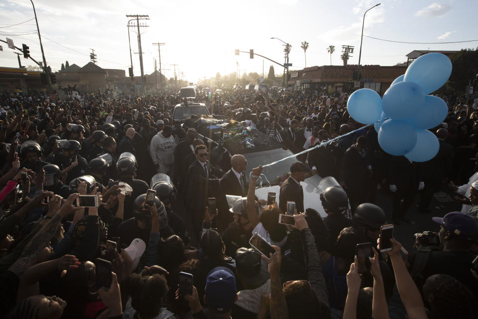 A hearse carrying the casket of slain rapper Nipsey Hussle passes through a large crowd on its 25-mile trek through the streets of the city Thursday, April 11, 2019, in Los Angeles. Hussle was shot and killed March 31 outside his The Marathon clothing store in South Los Angeles. (AP Photo/Jae C. Hong)