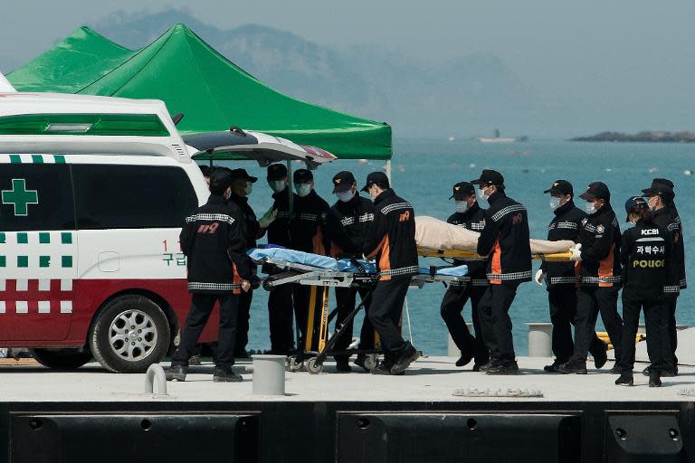 South Korean rescue team members carry the body of a victim recovered from the "Sewol" ferry to an ambulance at a harbour in Jindo on April 23, 2014