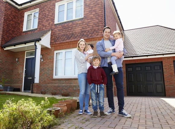 Young family standing in front of their home.