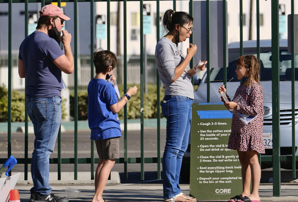 People swab their cheeks at a COVID-19 testing site in the North Hollywood section of Los Angeles on Saturday, Dec. 5, 2020. With coronavirus cases surging at a record pace, California Gov. Gavin Newsom announced a new stay-at-home order and said if people don't comply the state's hospitals will be overwhelmed with infected patients.(AP Photo/Richard Vogel)