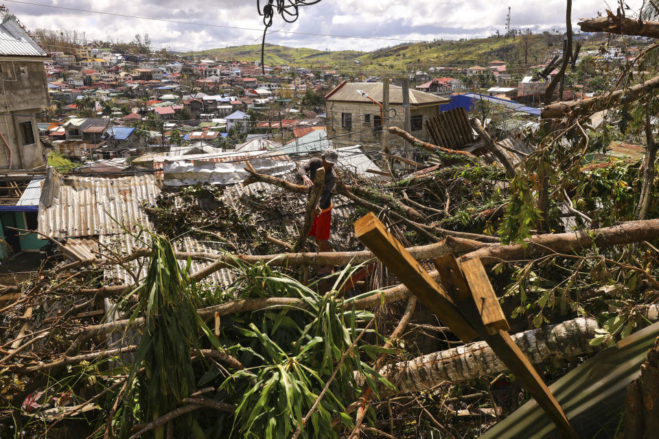 In this photo provided by Greenpeace, a man cleans out tree branches on top of their roof due to Typhoon Rai in Surigao City, southern Philippines Monday Dec. 20, 2021. The governor of a central Philippine province devastated by Typhoon Rai last week pleaded on radio Tuesday for the government to quickly send food and other aid, warning that without outside help, army troops and police forces would have to be deployed to prevent looting amid growing hunger. (Jilson Tiu/Greenpeace via AP)