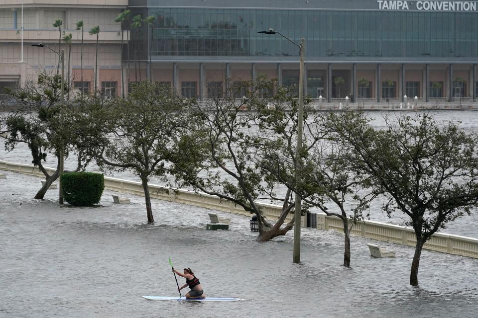 Zeke Pierce rides his paddle board down the middle of a flooded Bayshore Boulevard in downtown in Tampa, Florida (AP)