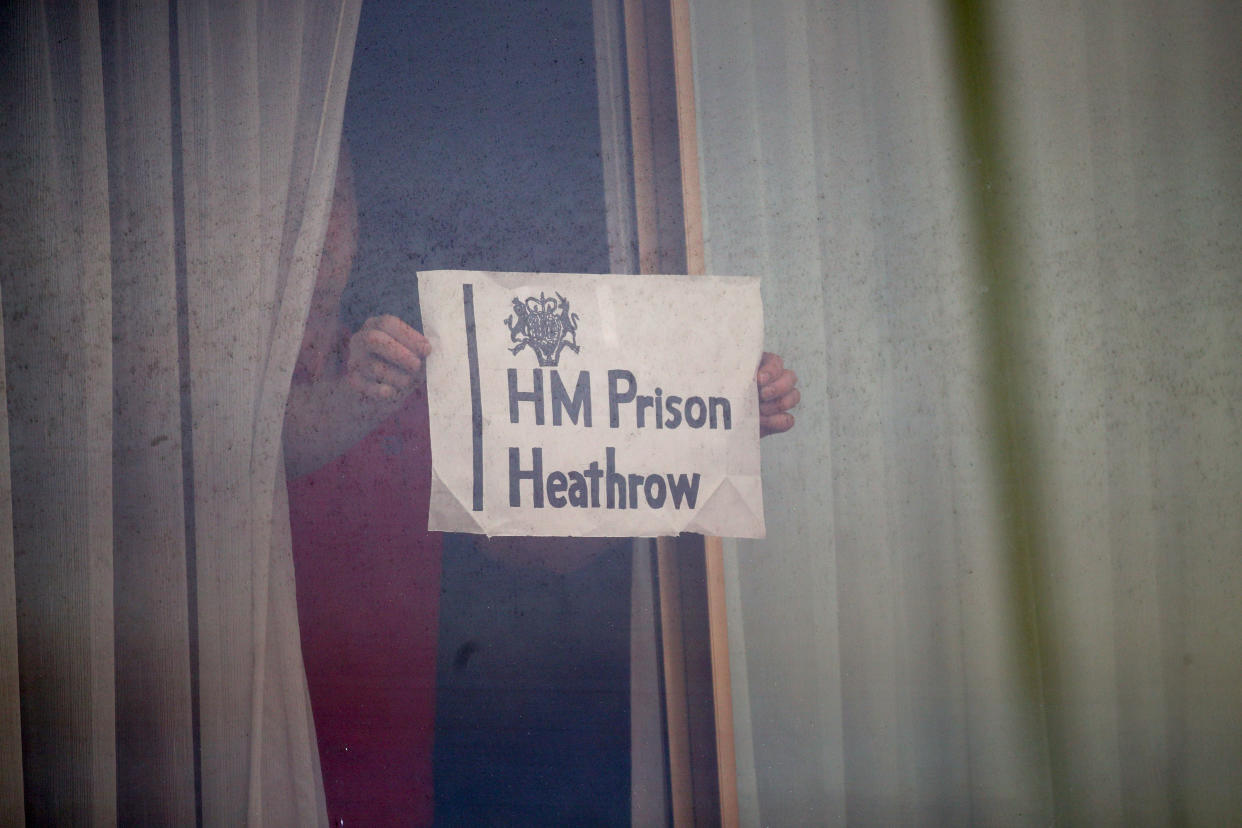 A man holds a sign against a window at the Renaissance London Heathrow Hotel, near Heathrow Airport, London, a Government-designated quarantine hotel being used for travellers to stay during a 10-day quarantine after returning to England from one of 33 