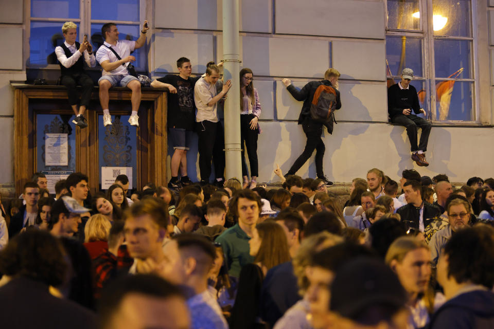 People climb a building to watch a show on the Neva River during the Scarlet Sails festivities marking school graduation in St. Petersburg, Russia, early Saturday, June 25, 2022. The Scarlet Sails celebration is a rite of passage both figuratively and literally. Every year, tall ships with glowing red sails make their way down the Neva River in St. Petersburg to honor recent school graduates as they set out on the journey into adulthood. (AP Photo/Elena Ignatyeva)