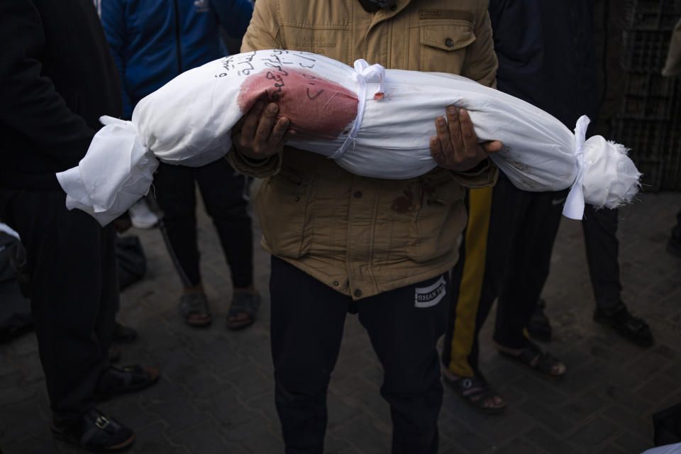 A man holds the body of his daughter who was killed in the Israeli bombardment of the Gaza Strip, at a hospital morgue in Rafah, Wednesday, Feb. 21, 2024. (AP Photo/Fatima Shbair)